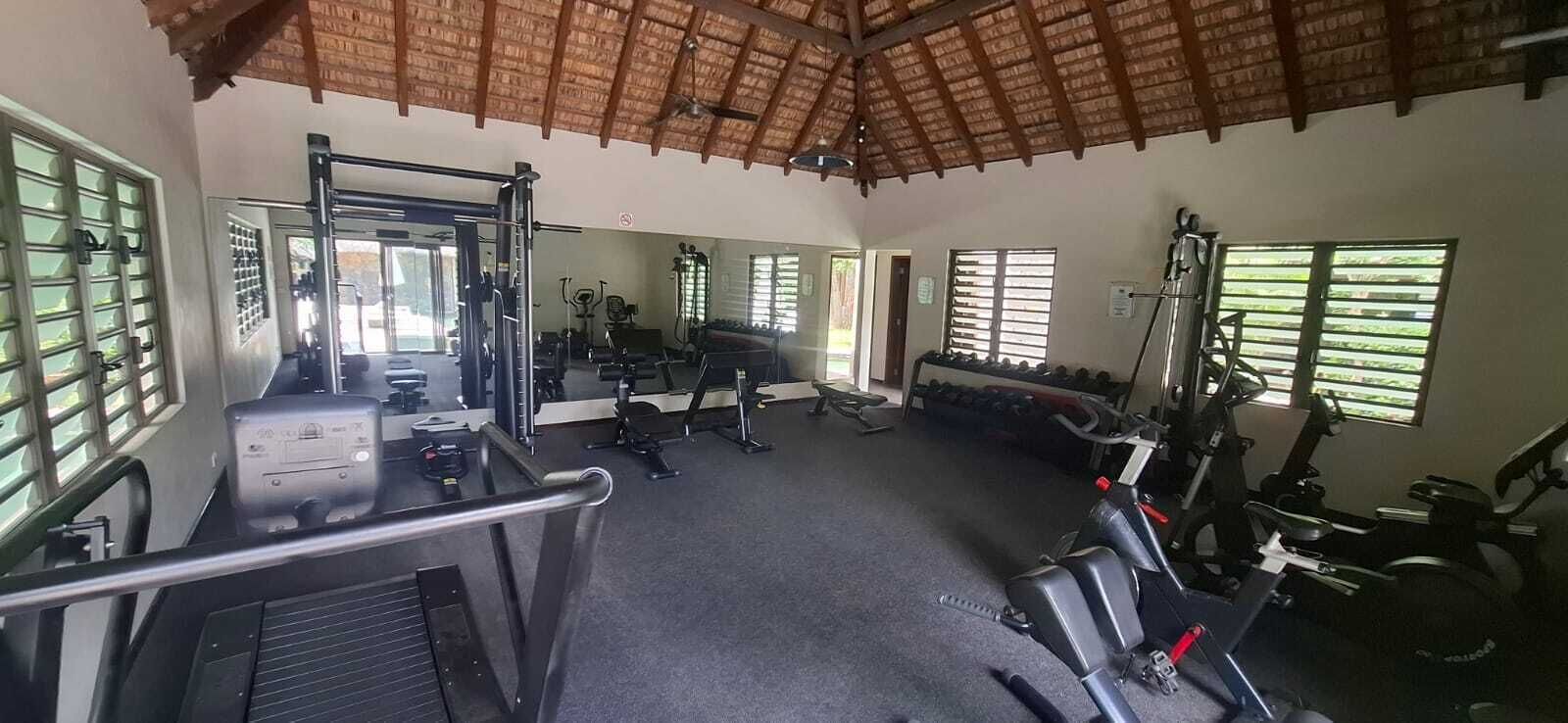 Une salle de sport équipée de matériel d’exercice, dotée d’un murmiroir et de grandes fenêtres.