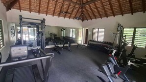 Un gimnasio con equipo de ejercicio, un espejo grande y amplias ventanas.