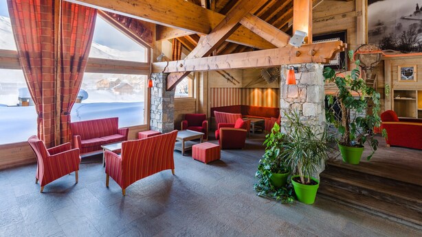 A wooden interior with red seating, stone pillars, and a view of a snowy landscape. - Mountain Escape in La Toussuire (Fontcouverte-la-Toussuire)