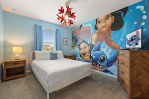 Un dormitorio con cama, mesitas de noche, una lámpara, un aparador y un mural en la pared.
