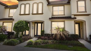 A multi-story residential building with a symmetrical facade, large windows, and a well-maintained garden. - Upstay Modern Home Near Disney With Pool (Kissimmee)