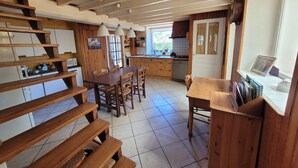 Una cocina con armarios de madera, una mesa de comedor y una escalera.