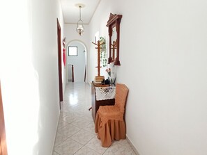 A hallway with a wooden door, a mirror, and a small table with a cloth. - Escape to this Sea View Apartment close to Kalymnos Climbing Routes (KALYMNOS)