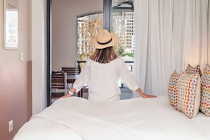 Ein Hotelzimmer mit einem Bett, einem Fenster mit Blick auf Gebäude, einem Sessel und einem Tisch.