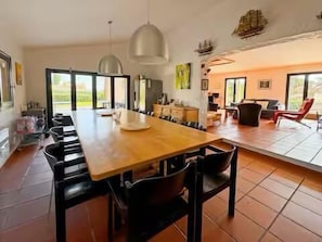 A spacious dining area with a long wooden table, black chairs, and pendant lighting. - Provençal villa by the sea in Les Issambres (Roquebrune-sur-Argens)