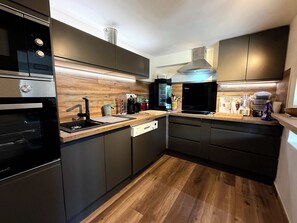 Eine moderne Küche mit eingebauten Geräten, Holzboden und dunklen Schränken.