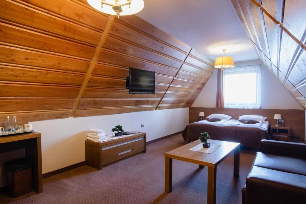 Un cuarto ático acogedor con techo de madera, una cama, un escritorio y un televisor.