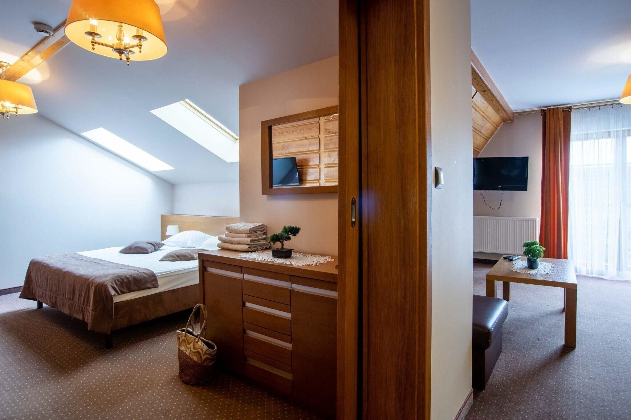A bedroom with a bed, a dresser, a desk, a chair, a television, and a window.