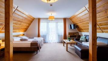 A room with a bed, a sofa, a table, and a TV.