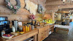 A buffet setup with a wooden counter, various food items, and a rustic interior with stone flooring and wooden walls. - Witowianka (Koscielisko)