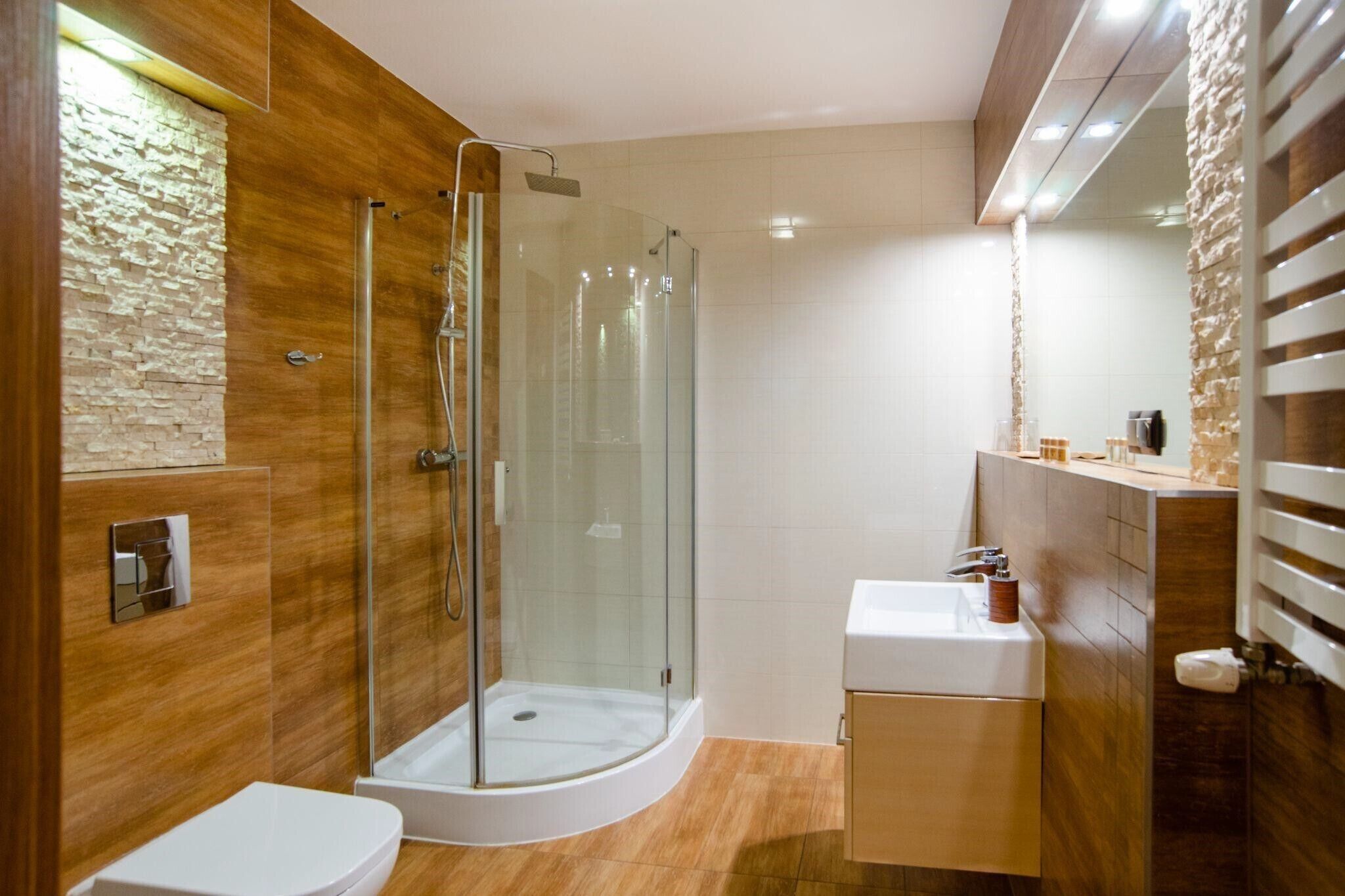 A modern bathroom with a glass-enclosed shower, a white sink, and wooden paneling.