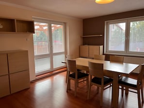 Comedor con mesa, sillas, un armario y ventanas grandes con persianas.