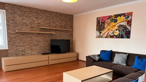 A modern living room with a TV, sofa, and artwork on the wall.