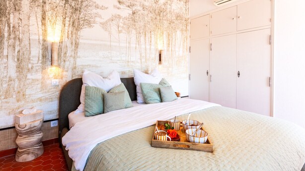A bedroom with a bed, pillows, a tray with bowls, a toilet, and a wardrobe. - BELLEROSE HOUSE IN HAMLET (Le Plan-de-la-Tour)