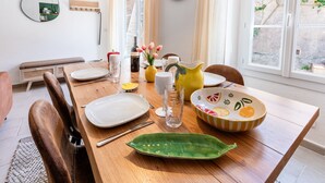 A dining table set with plates, glasses, and a pitcher, with a chair and a bench in the background. - BELLEROSE HOUSE IN HAMLET (Le Plan-de-la-Tour)
