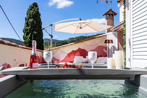 A poolside setting with a table, wine bottle, glasses, strawberries, and a decorative umbrella. - BELLEROSE HOUSE IN HAMLET (Le Plan-de-la-Tour)