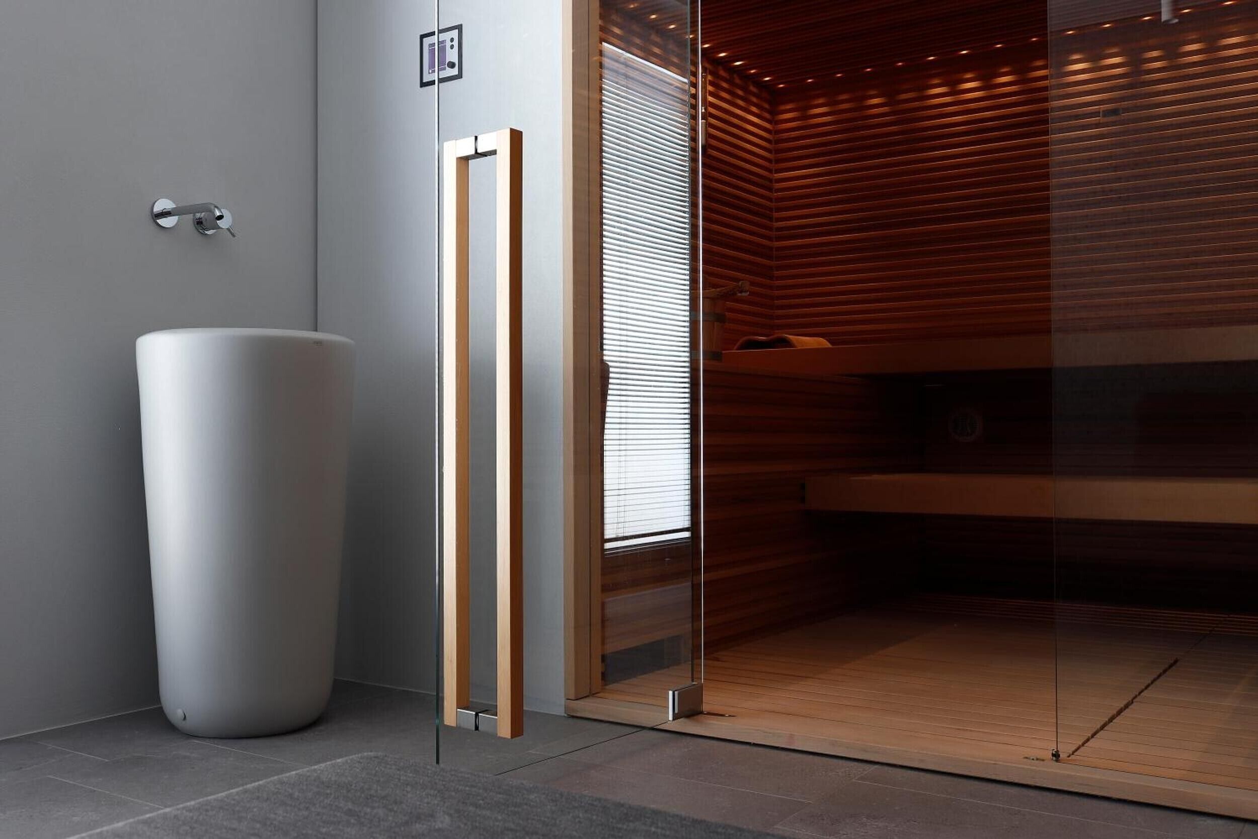Ein modernes Badezimmer mit einem großen weißen Waschbecken, einer Duschkabine aus Glas und Holzvertäfelung.