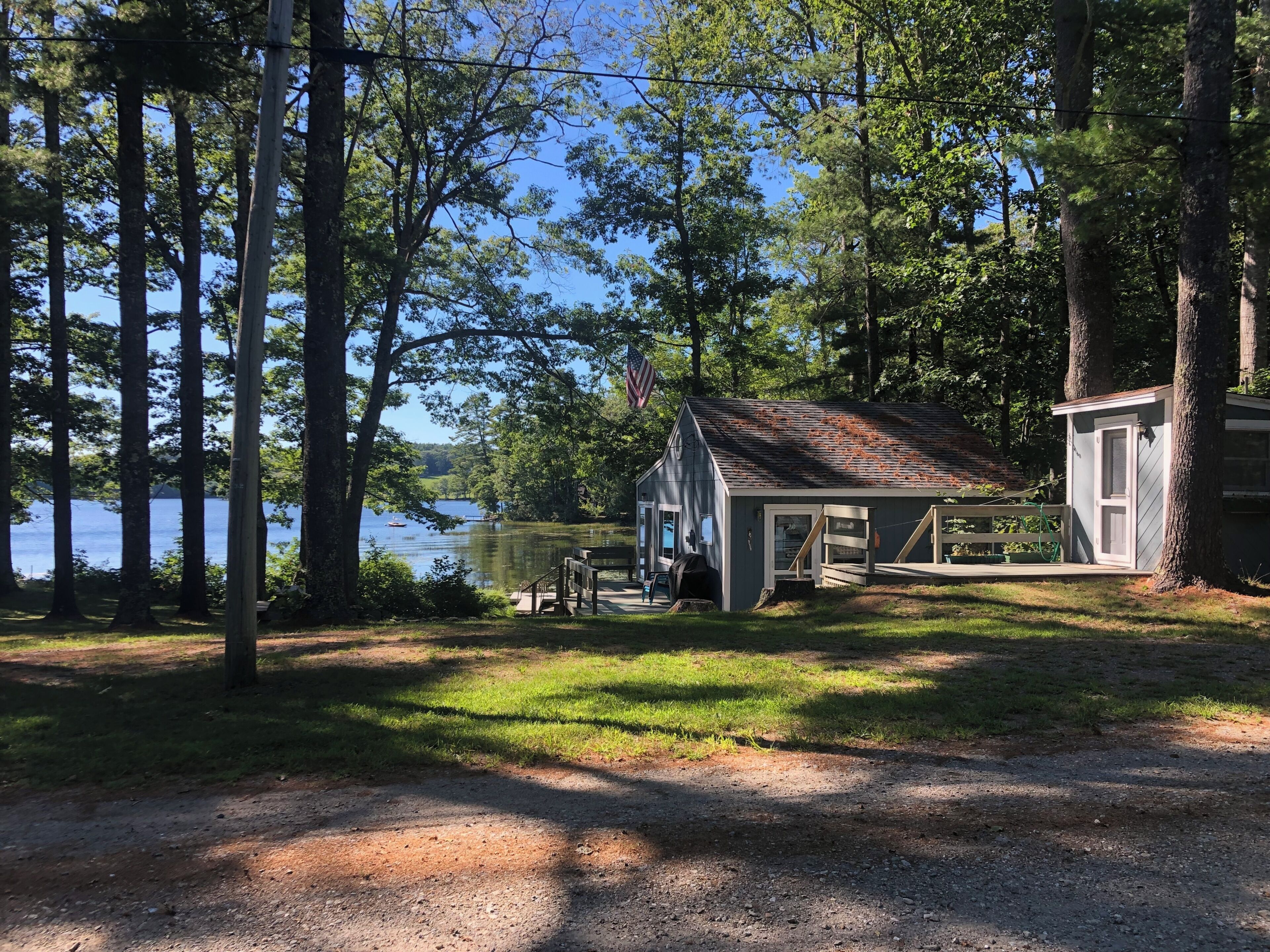 A cabin with a dock, surrounded by trees and a lake.