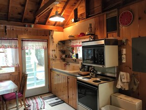 A kitchen with wooden cabinets, a stove, a microwave, and a sink.