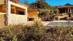 Una casa con facciata in pietra, un patio con mobili da esterno e una piscina.