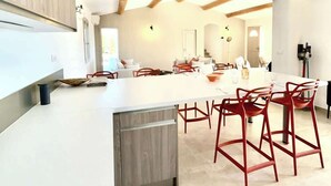 Una cucina moderna con isola centrale, sgabelli rossi e travi a vista in legno.