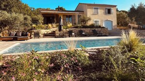 Una casa con piscina, area relax esterna e un muro in pietra.