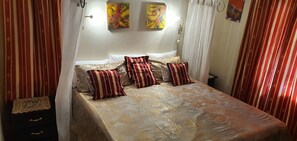 Una cama con ropa de cama estampada, almohadas a rayas y un cabecero.