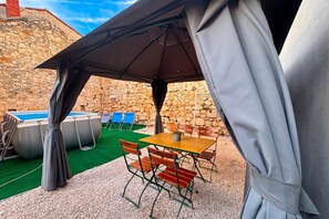 An outdoor patio with a pool, chairs, and a table under a tent. - Casa Valdebek With Pool (Pula)