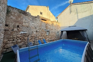 A stone wall, a swimming pool, and a building with a satellite dish. - Casa Valdebek With Pool (Pula)