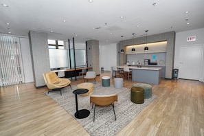 A modern hotel lobby with a reception desk, seating area, and a kitchenette.