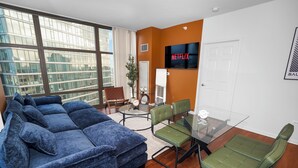 A modern living room with a sectional sofa, a glass coffee table, and a green chair. - 25th Floor 2BR Grant Park Suite with Balcony (Chicago)