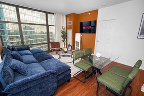 Una sala de estar moderna con un sofá modular, una mesa de centro de vidrio y una silla verde.