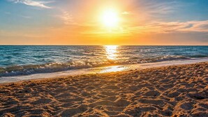 A beach with sand and water, a sunset, and a clear sky. - Stylish 2BR/2BA coastal getaway to 7 Min Drive to Beach "Crystal Bay Stays" (Englewood)