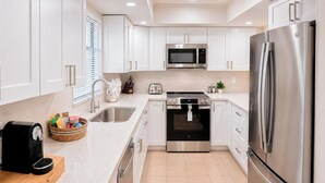 A modern kitchen with white cabinets, stainless steel appliances, a toaster, and a coffee maker. - Stylish 2BR/2BA coastal getaway to 7 Min Drive to Beach "Crystal Bay Stays" (Englewood)