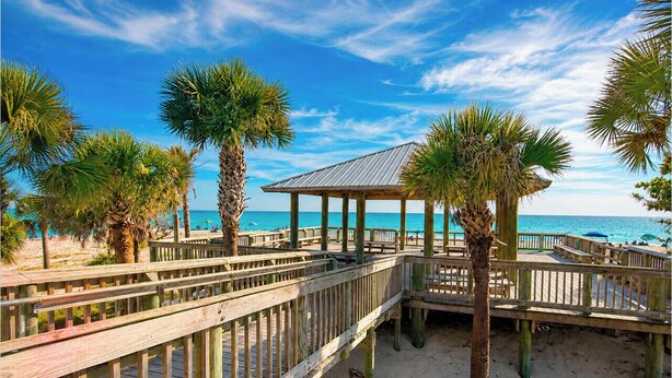 A wooden boardwalk leading to a beach with palm trees and a covered pavilion. - Stylish 2BR/2BA coastal getaway to 7 Min Drive to Beach "Crystal Bay Stays" (Englewood)