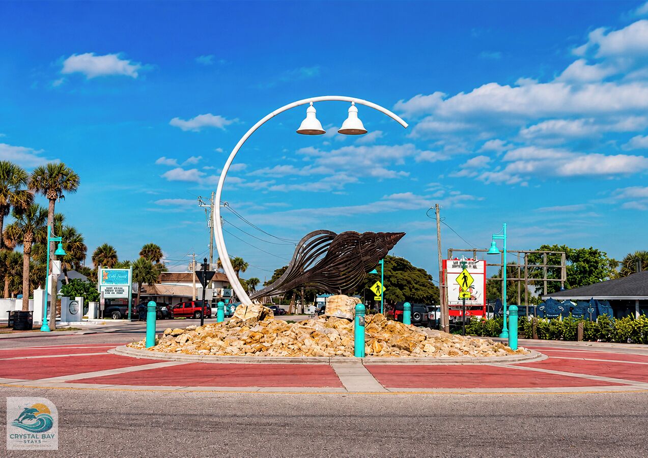 A street intersection with a unique metal sculpture, a red road, and a clear blue sky.