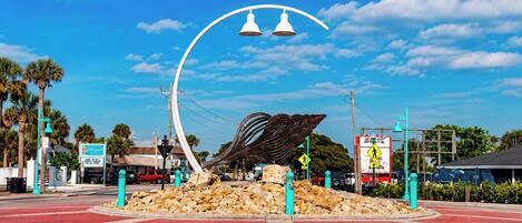 A street intersection with a unique metal sculpture, a red road, and a clear blue sky.