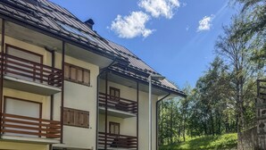 A two-story building with a balcony, a stone pathway, and a grassy area. - Casa Castoro - In the heart of Val di Peio (Peio Fonti)