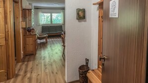 A hallway with wooden flooring, a bench, a small table, and a door with a sign. - Casa Castoro - In the heart of Val di Peio (Peio Fonti)