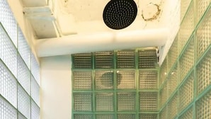 Un baño con pared de azulejos, un separador verde y dos botellas en la pared.