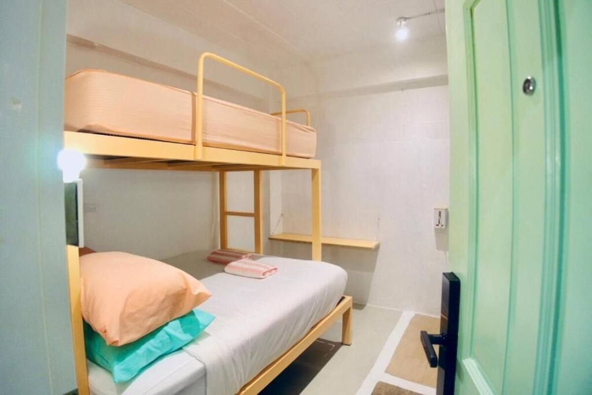 Habitación con literas, un escritorio y una puerta verde.