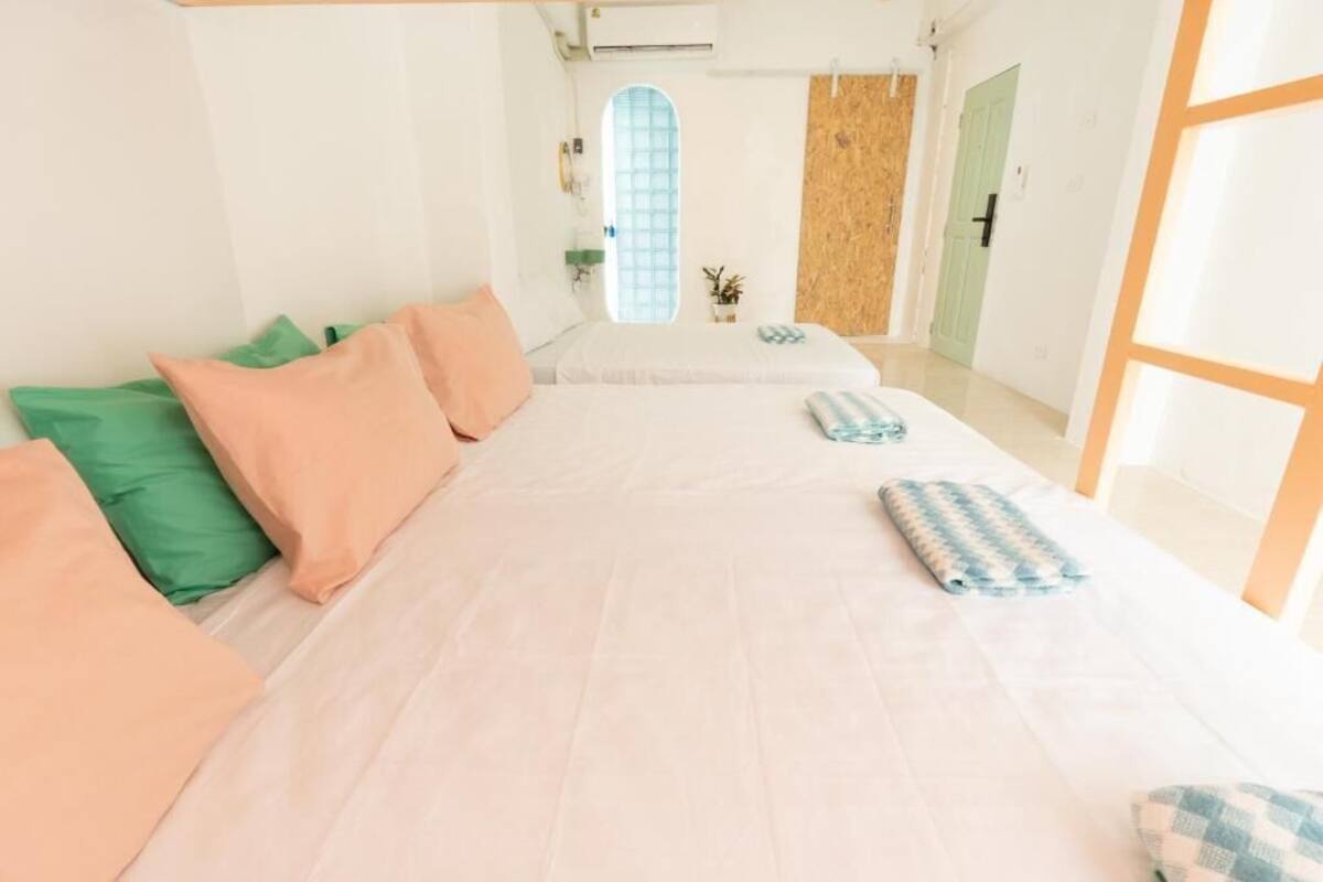 Una habitación con una cama grande, una mesita y un ventanal con vistas a un edificio.