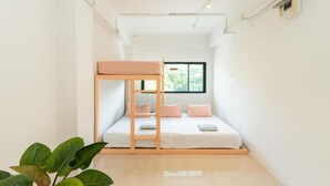 Una habitación pequeña y luminosa con una litera, una ventana y una planta.