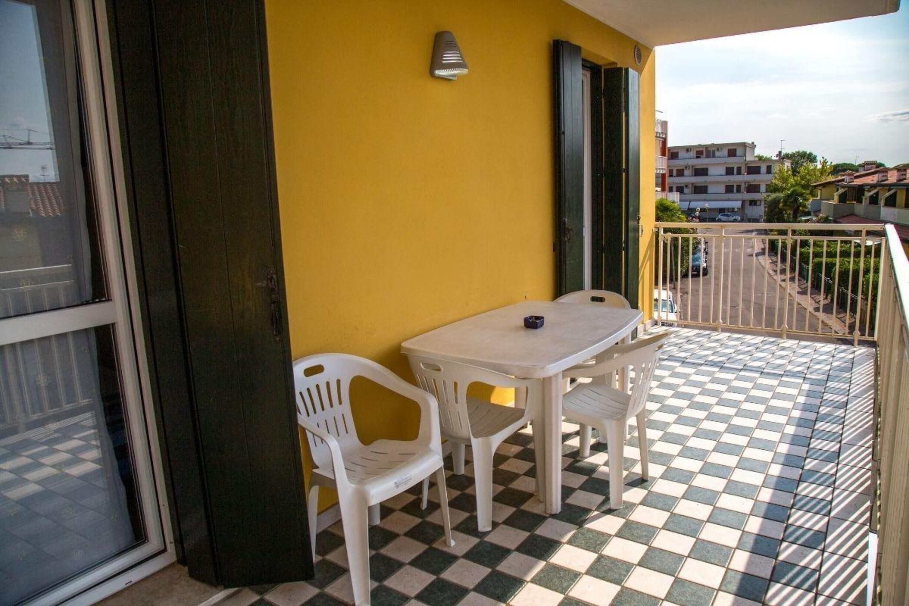 Ein Balkon mit kariertem Boden, einem Tisch, Stühlen und einer gelben Wand.
