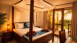 A four-poster bed with a canopy, a dining table with chairs, a small table with a candle, and a view of palm trees and the ocean. - Moayana Liora Zanzibar · Pongwe · Beachfront - Authentic (Zanzibar)