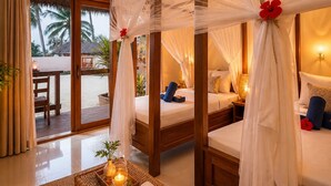 A room with a bed, a table with candles, and a view of palm trees. - Moayana Liora Zanzibar · Pongwe · Beachfront - Authentic (Zanzibar)