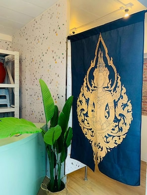 Una habitación con una pared moteada, una cortina azul con un emblema dorado, una planta verde y un estante blanco.