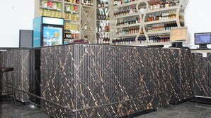 A bar area with shelves of beverages, a counter with a patterned design, and a beverage dispenser. - Ehtans Hotel And Accommodations (Eldoret)