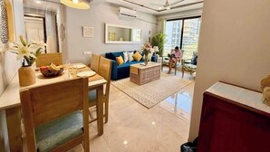 Un salon moderne comprenant un coin repas, un canapé bleu, une table basse et une personne qui lit.