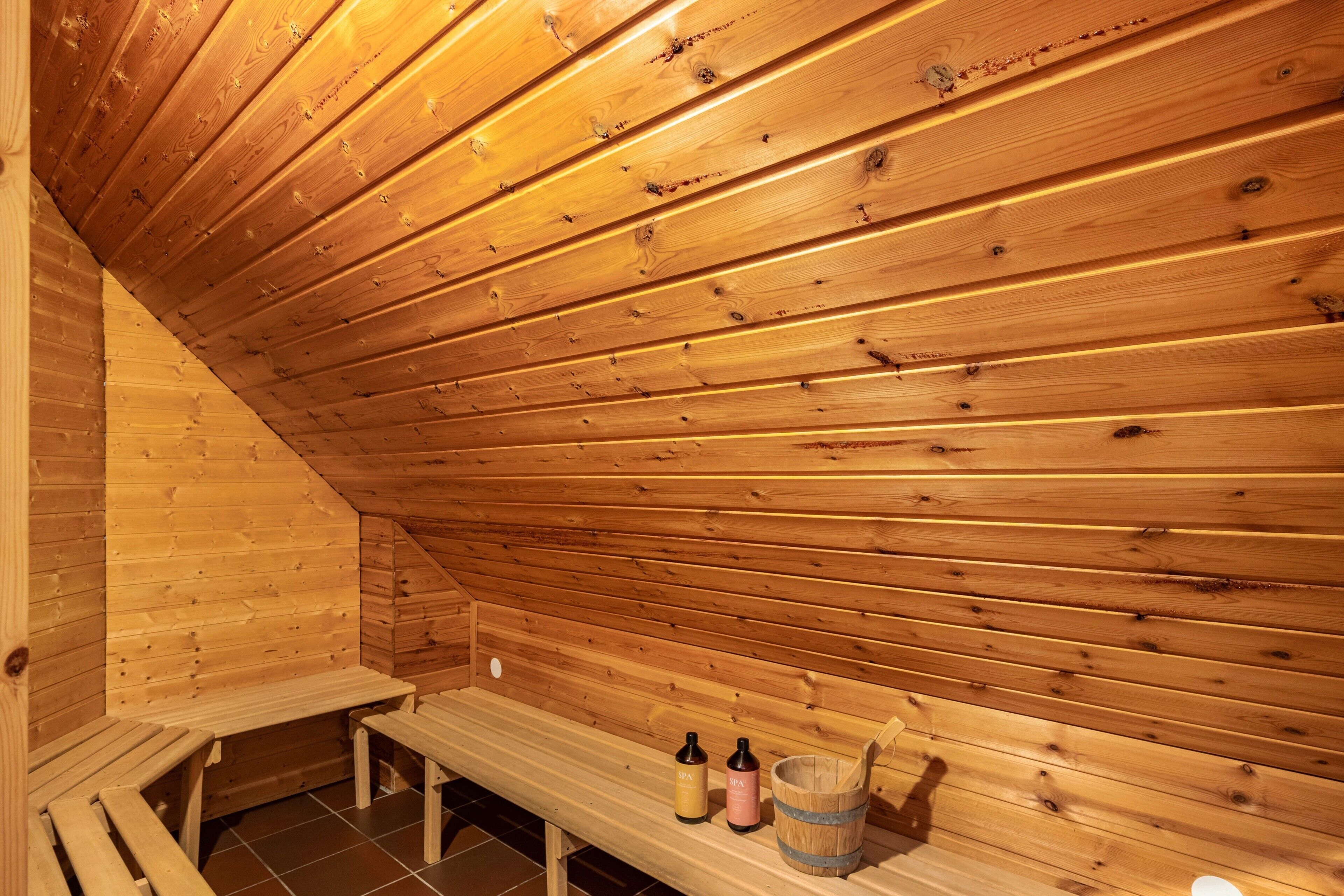 Eine Holzsauna mit Bänken, zwei Flaschen und einem Holzeimer.